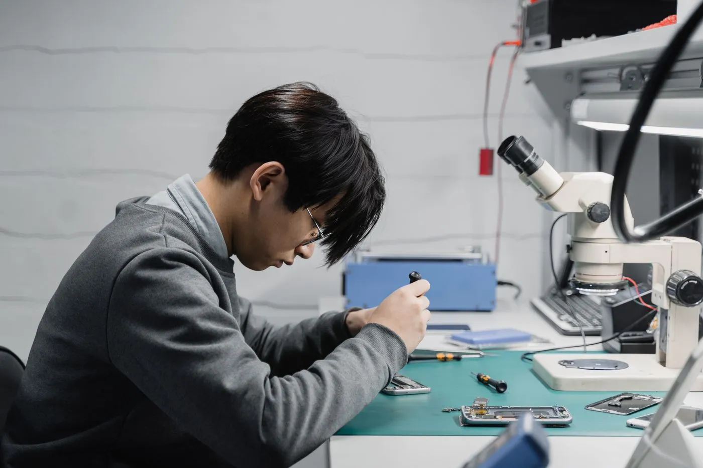 Technician inspecting a device under a microscope